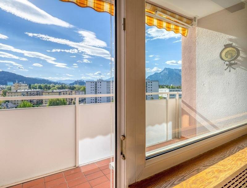 Balkon mit Markise und weitem Blick über die Stadt und die umliegende Berglandschaft.