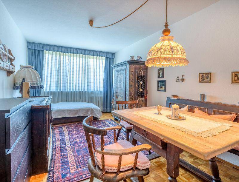 Schlafzimmer mit traditionellen Holzmöbeln, Teppich und Blick ins Grüne.