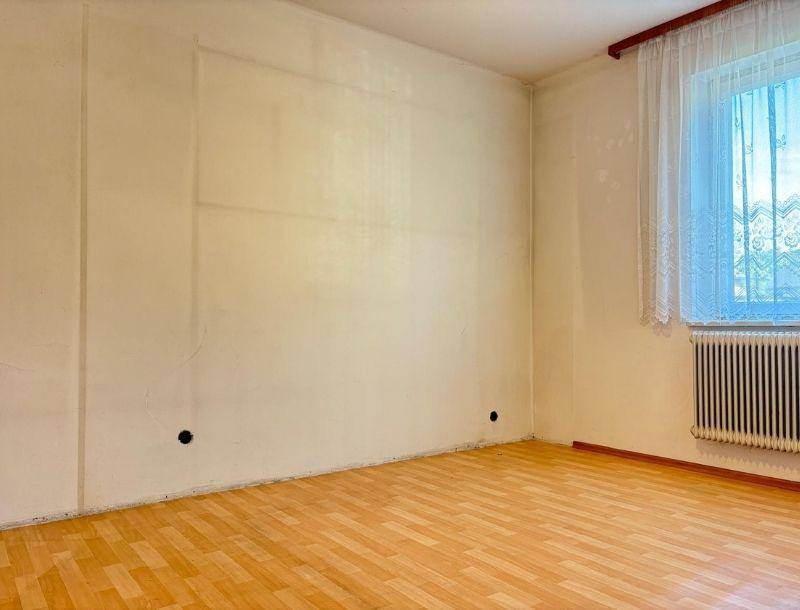 Leerer Raum mit hellen Wänden, Fenster mit Vorhängen und Laminatboden, bereit zur individuellen Gestaltung.