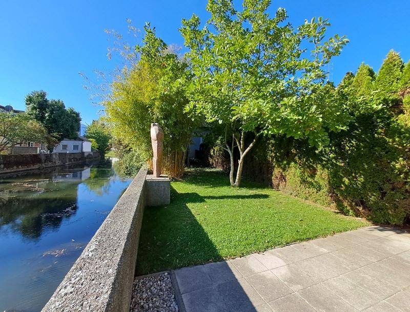 Gepflegter Gartenbereich am Wasser mit üppiger Bepflanzung und sonnigem Ambiente.