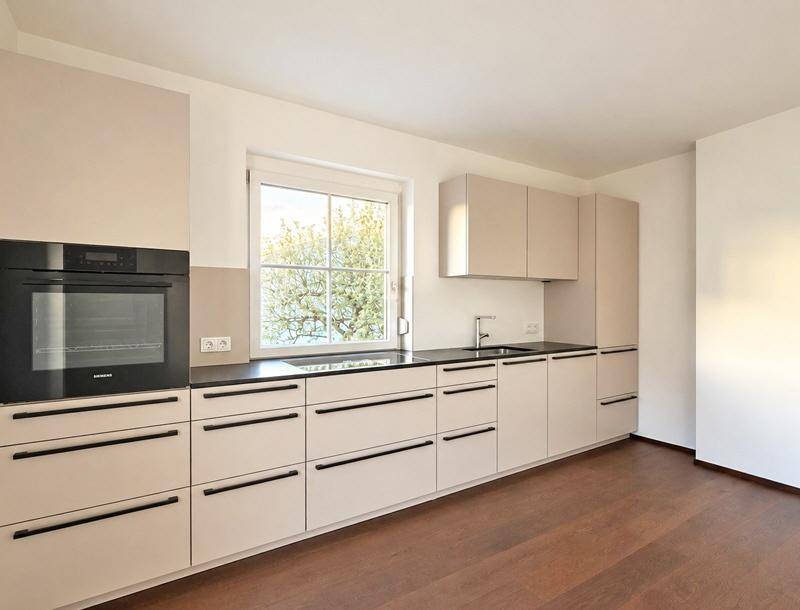 Moderne Einbauküche in hellem Beige mit dunkler Arbeitsplatte und integrierten Siemens-Geräten, bereit zur Nutzung.