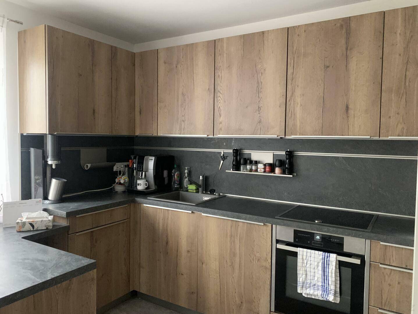 Geräumige Küche mit Holzschränken, dunkler Arbeitsplatte und modernen Geräten.