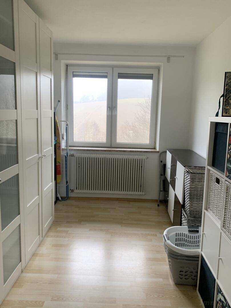 Heller Hauswirtschaftsraum mit Fenster, Laminatboden und praktischen Regalsystemen.