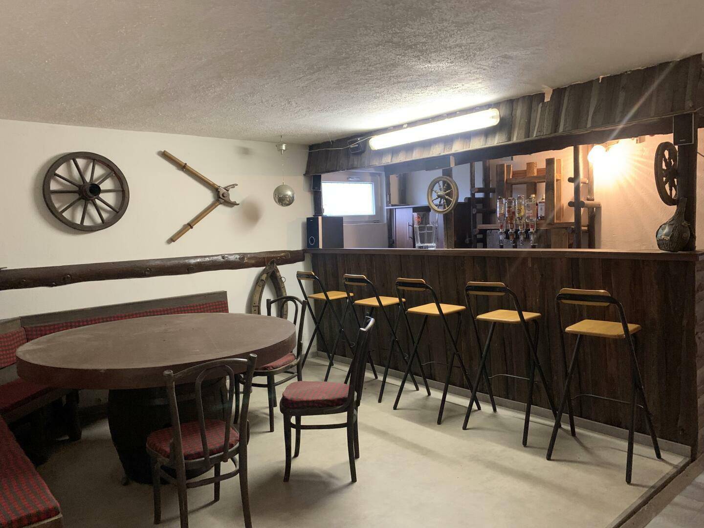 Rustikaler Partyraum im Keller mit Bar, Sitzgelegenheiten und Holzelementen.