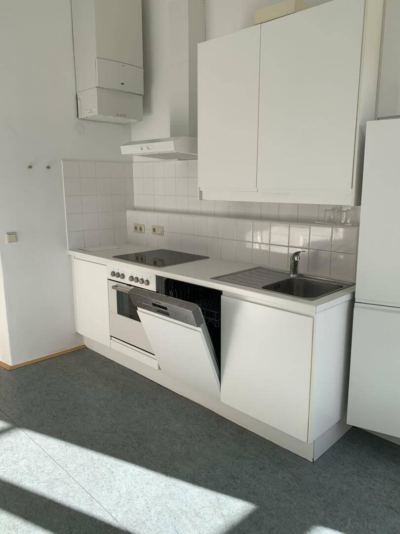 Funktionale weiße Einbauküche mit modernen Geräten, Fliesenrückwand und Hängeschränken.