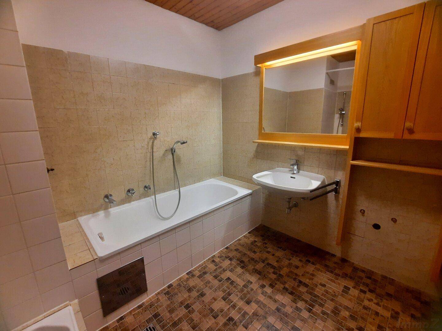 Badezimmer mit Badewanne, Waschbecken und Holzdecke in traditionellem Stil.