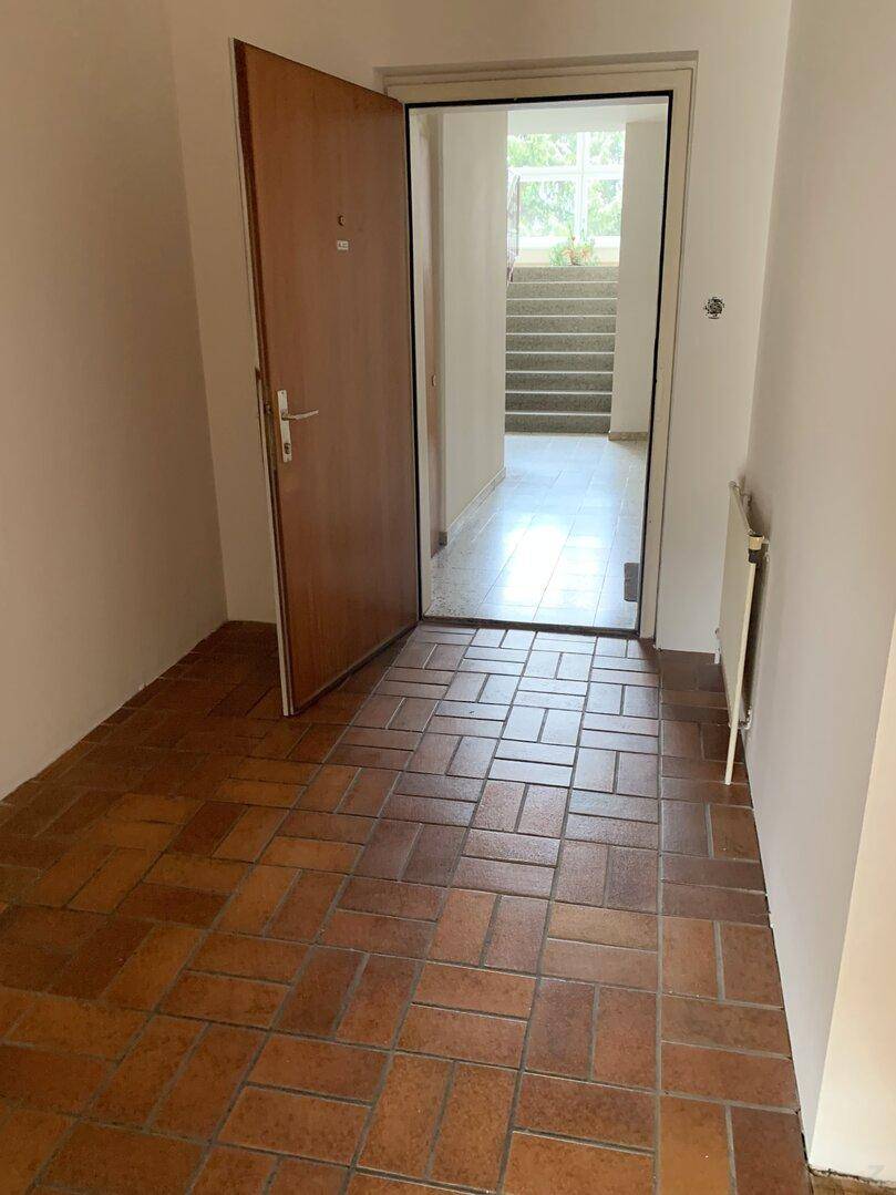 Eingangsbereich mit Terrakotta-Fliesenboden und Blick auf das Treppenhaus.
