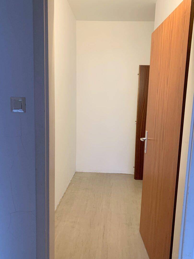 Leerer Abstellraum mit hellem Boden und Holztüren, ideal für zusätzlichen Stauraum.