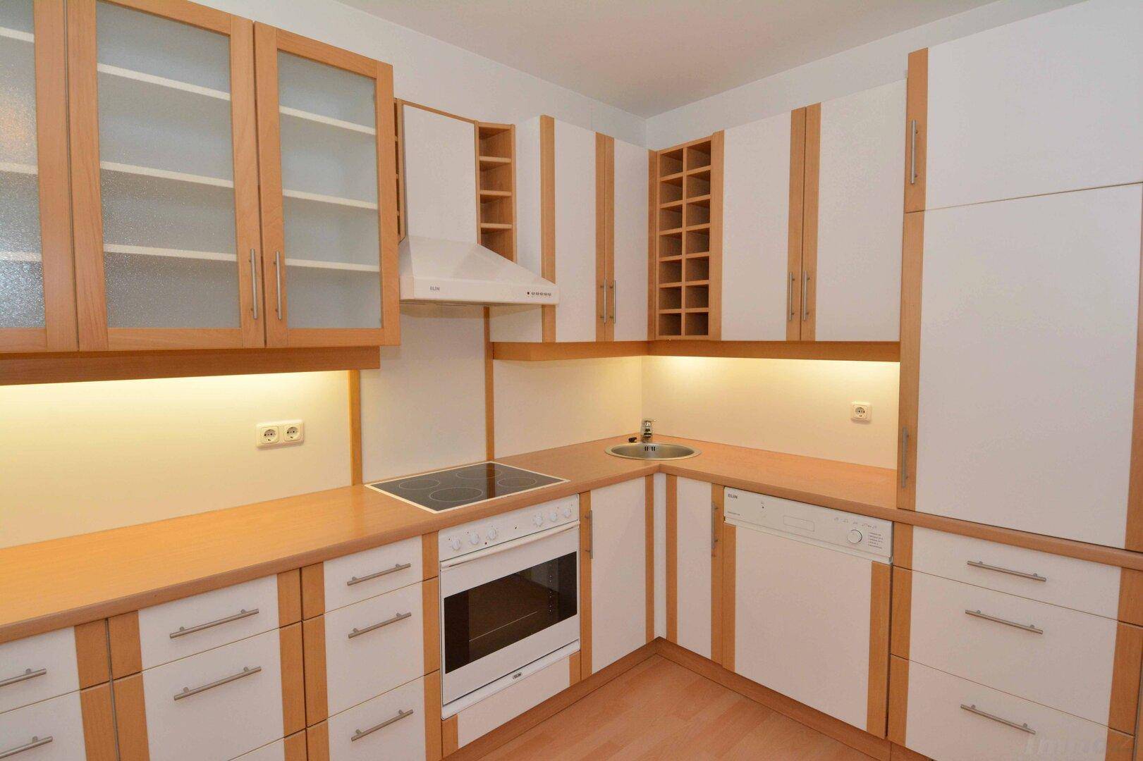 Helle Einbauküche mit hellen Holzfronten, integrierten Geräten und viel Stauraum.
