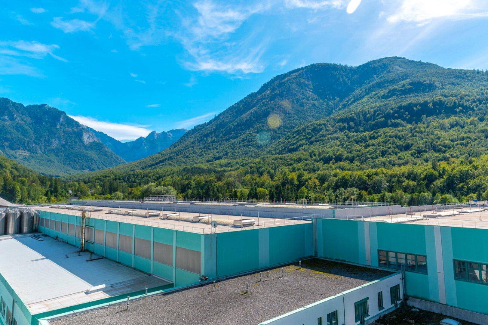 Dachansicht eines weitläufigen Industriegebäudes vor einer beeindruckenden Berglandschaft.