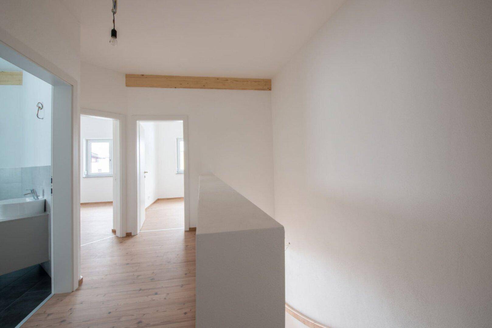 Heller Flur im Obergeschoss mit Holzboden und Zugang zu verschiedenen Zimmern.