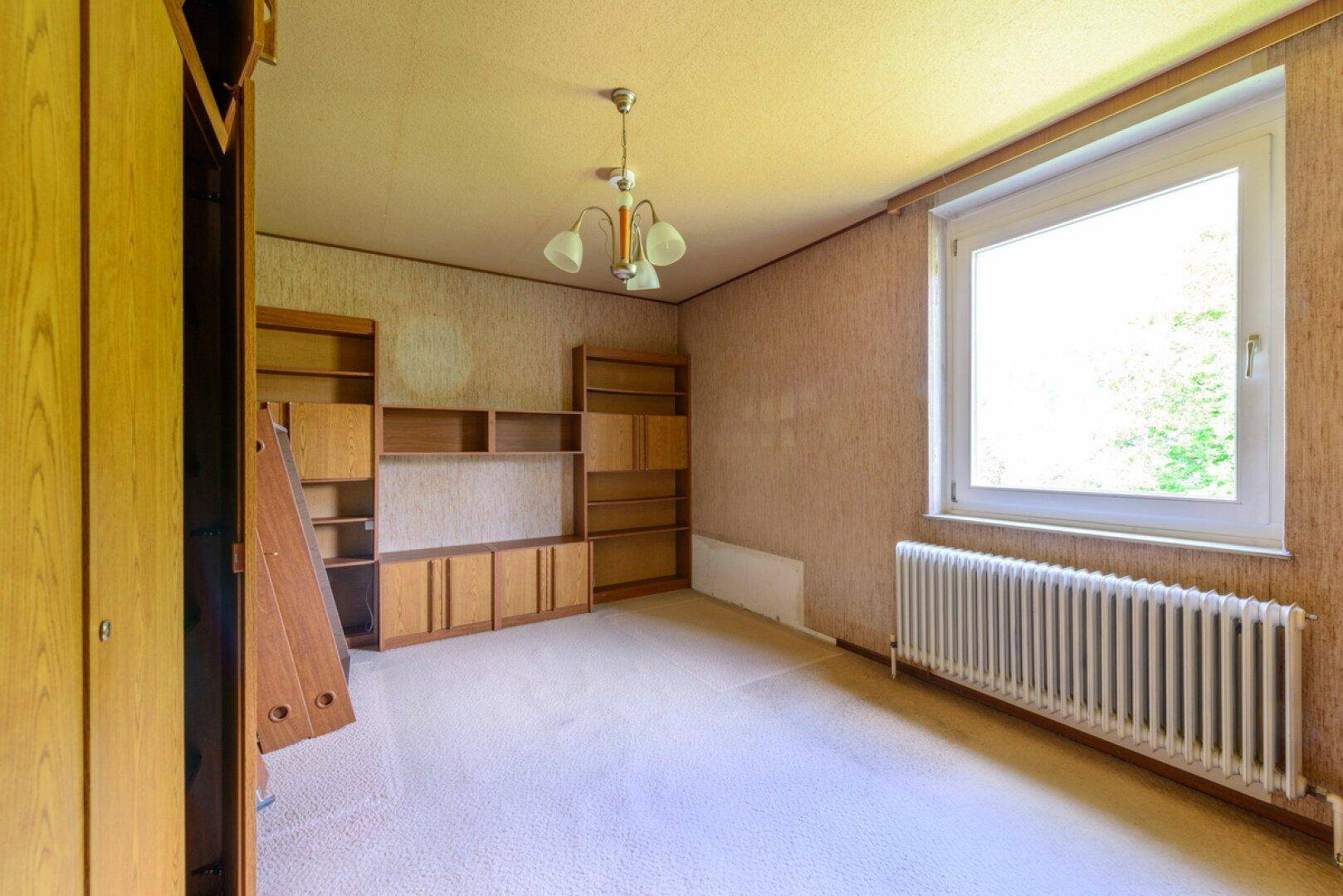 Schlafzimmer mit Teppichboden, großem Fenster und Einbauschränken.