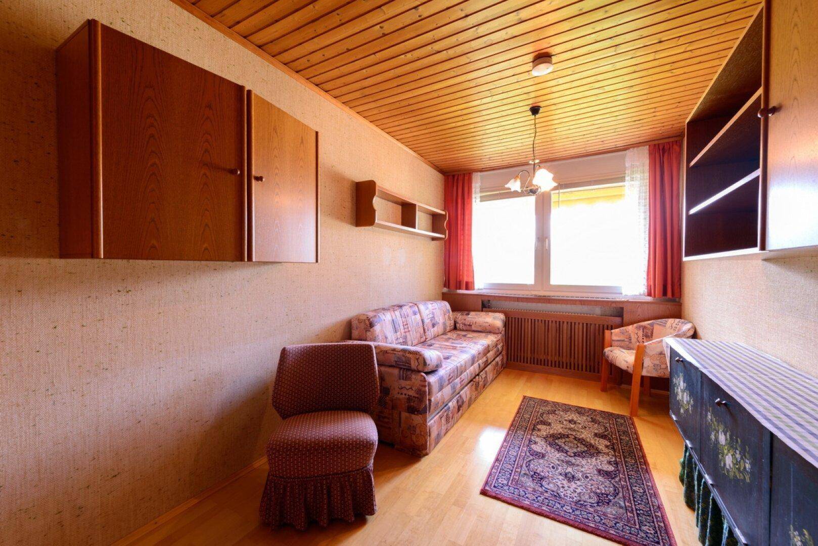 Gemütliches Wohnzimmer mit Holzdecke, Parkettboden und traditionellen Möbeln.