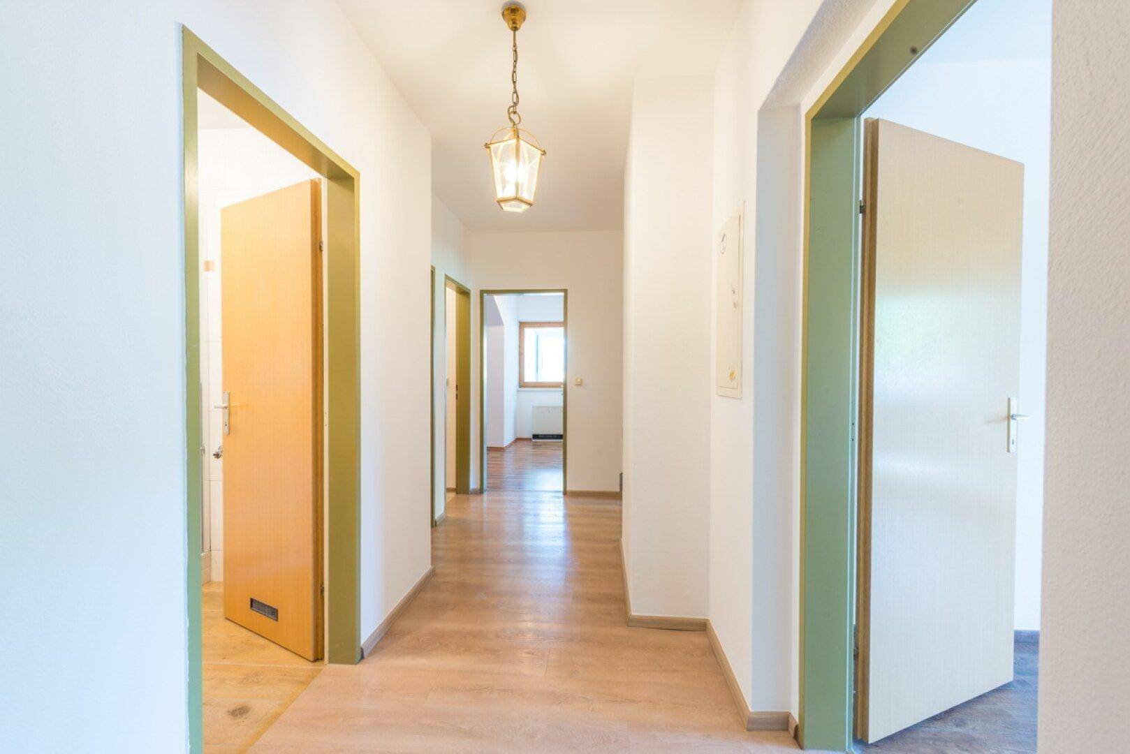 Helle Diele mit Holzboden und mehreren Türen, die zu verschiedenen Räumen führen.