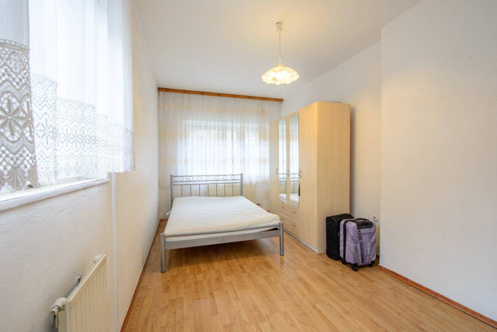 Helles Schlafzimmer mit Einzelbett, hellem Holzschrank und Holzboden, ideal als Gästezimmer.