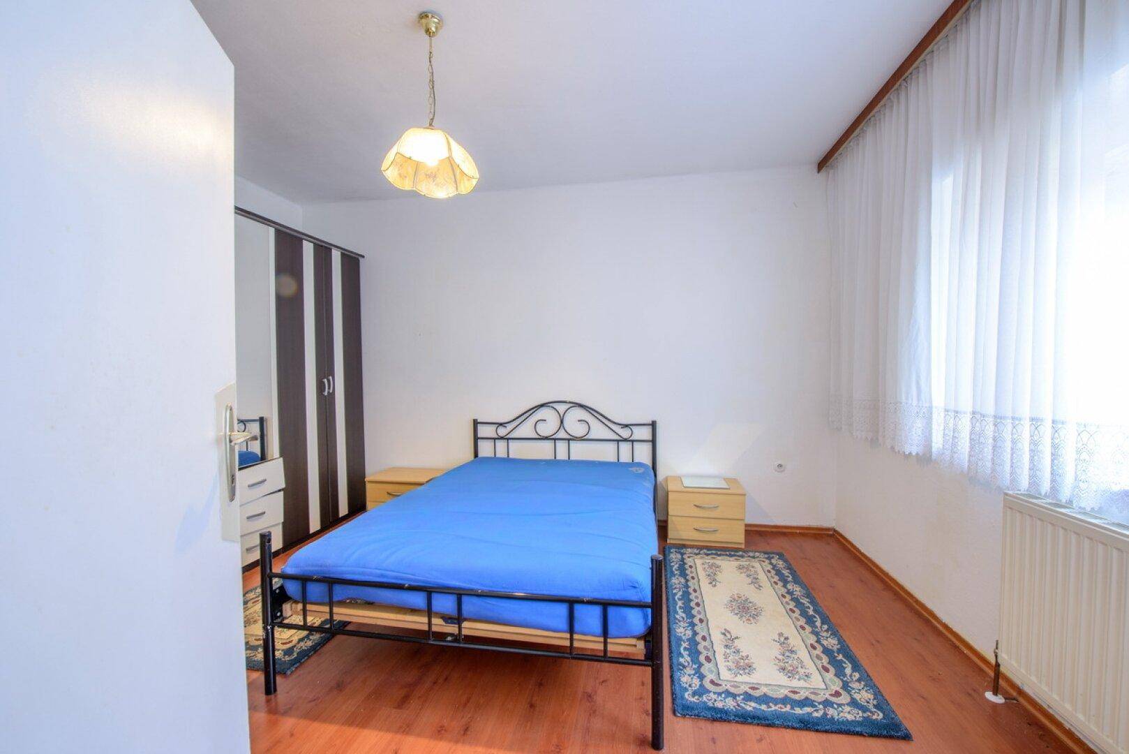 Schlafzimmer mit Doppelbett, Nachttischen und einem Kleiderschrank, ausgestattet mit Holzboden.