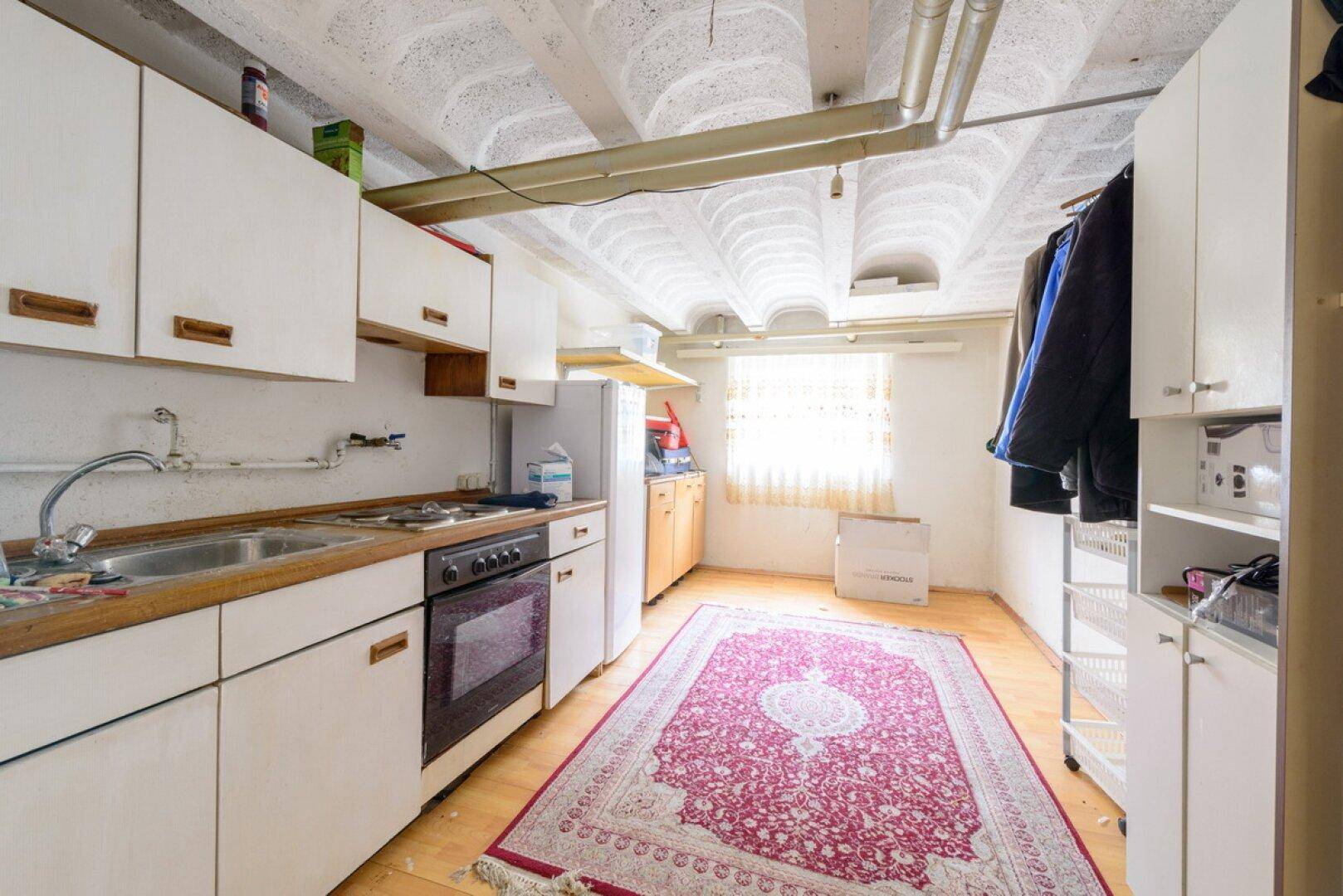 Hauswirtschaftsraum im Keller mit einfacher Küchenzeile, Fenster und Stauraum.