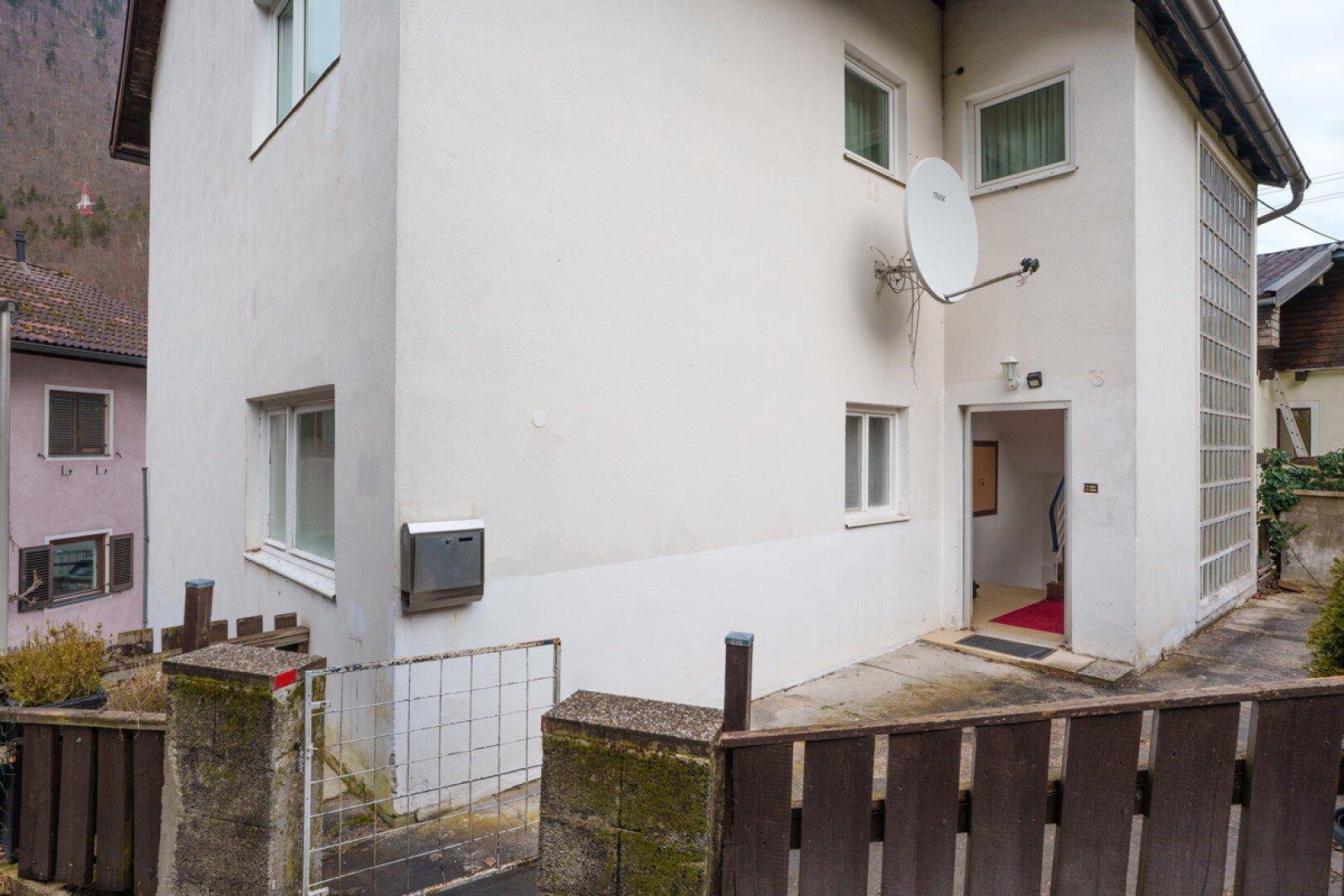 Eingangsbereich des Hauses mit Satellitenempfänger und Glasbausteinwand, die für Helligkeit sorgt.