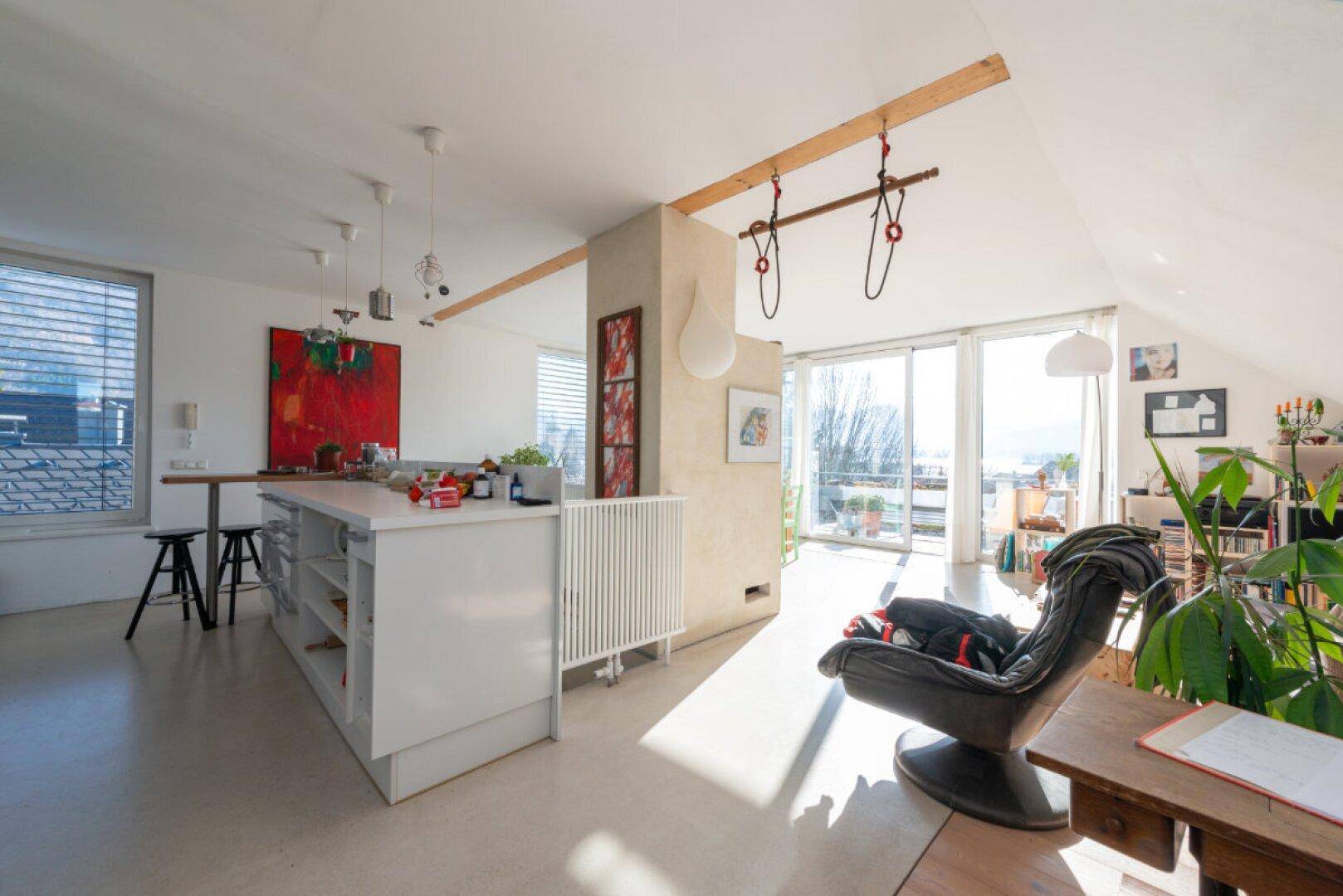 Offener Wohnbereich im Dachgeschoss mit viel Tageslicht und Zugang zur Terrasse.