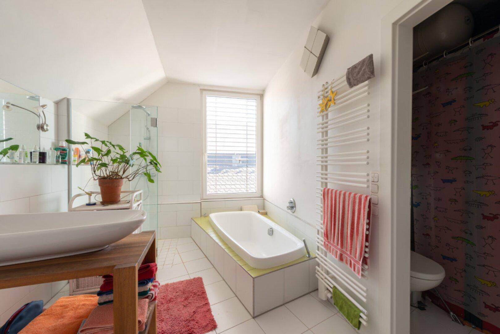 Modernes Badezimmer mit Badewanne, Dusche, Einzelwaschbecken und beheiztem Handtuchhalter.