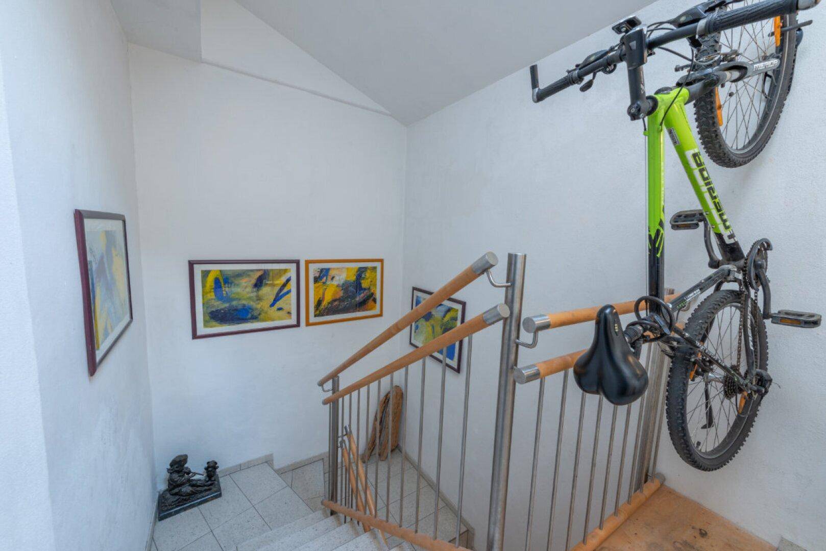 Treppenhaus mit modernem Geländer und Wandhalterung für ein Fahrrad.
