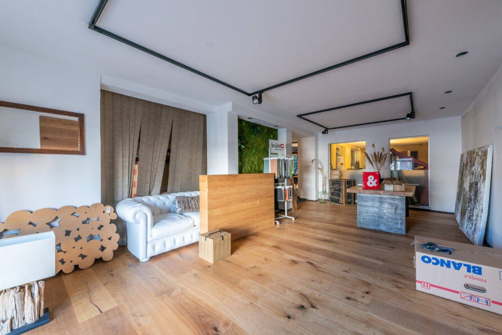 Großer offener Raum mit Holzboden und moderner Beleuchtung, möglicherweise ein Loft oder Büro.