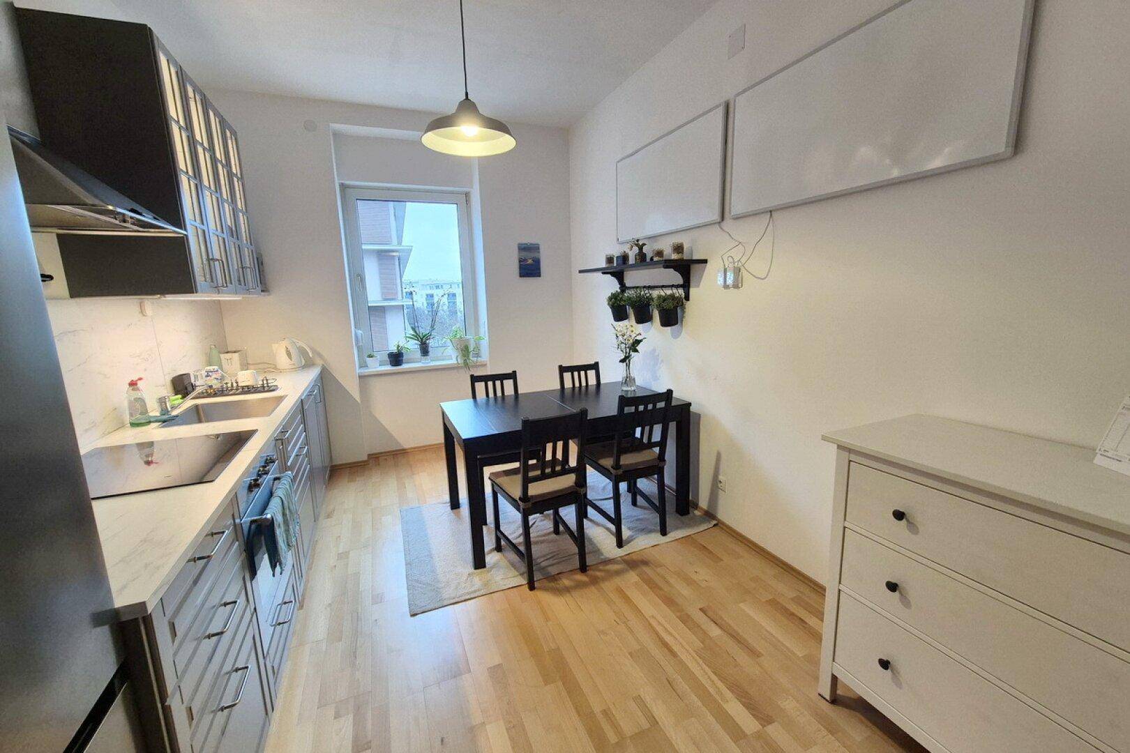 Funktionale Küche mit Essbereich, Holzfußboden und zwei Heizpaneelen an der Wand.