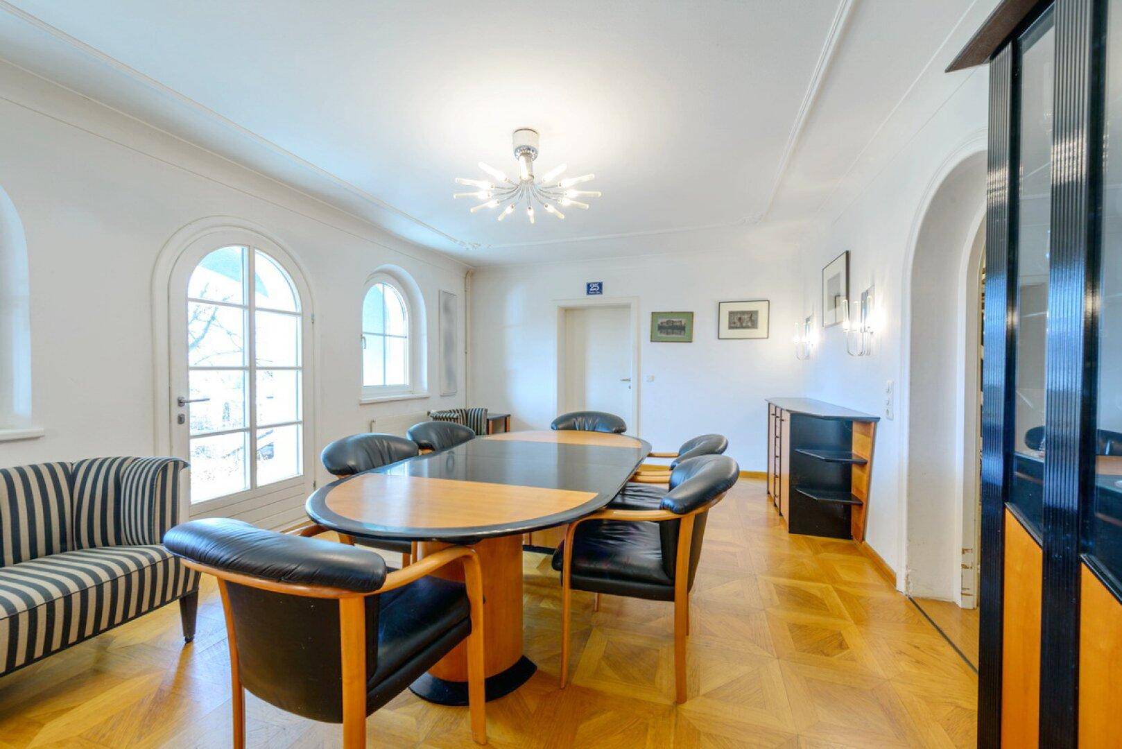 Eleganter Essbereich mit Parkettboden, Rundbogenfenstern und stilvollen Möbeln.