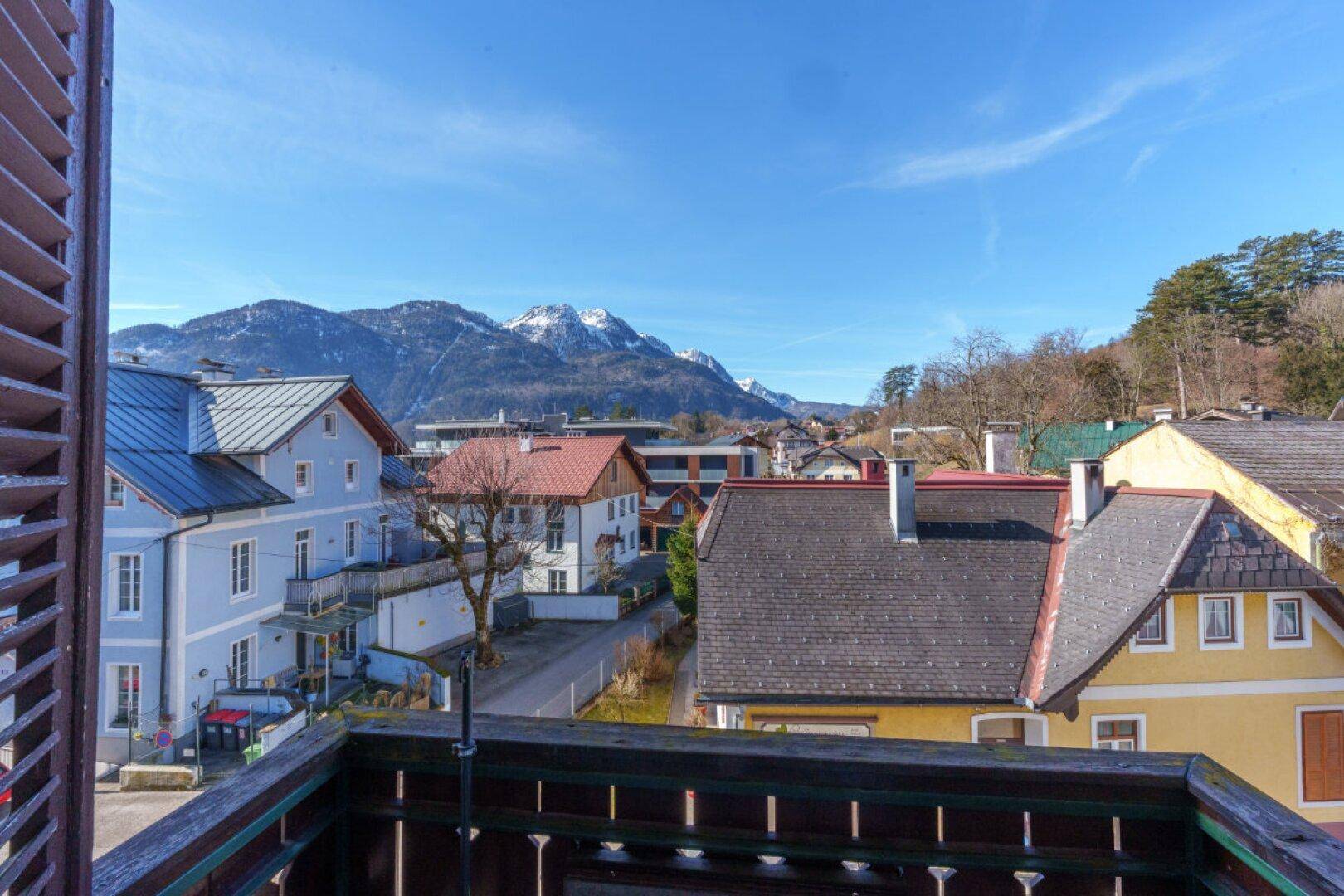 Blick vom Balkon auf die umliegende Berglandschaft und die Dächer der Stadt.