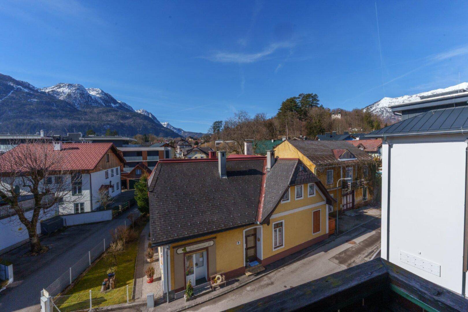 Panoramablick über die Dächer der Stadt mit schneebedeckten Bergen im Hintergrund.