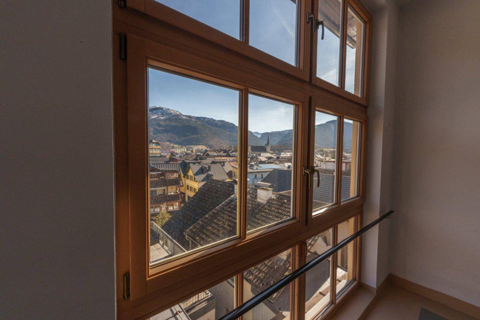 Große Holzfenster im Treppenhaus bieten einen weiten Blick auf die Stadt und Berge.