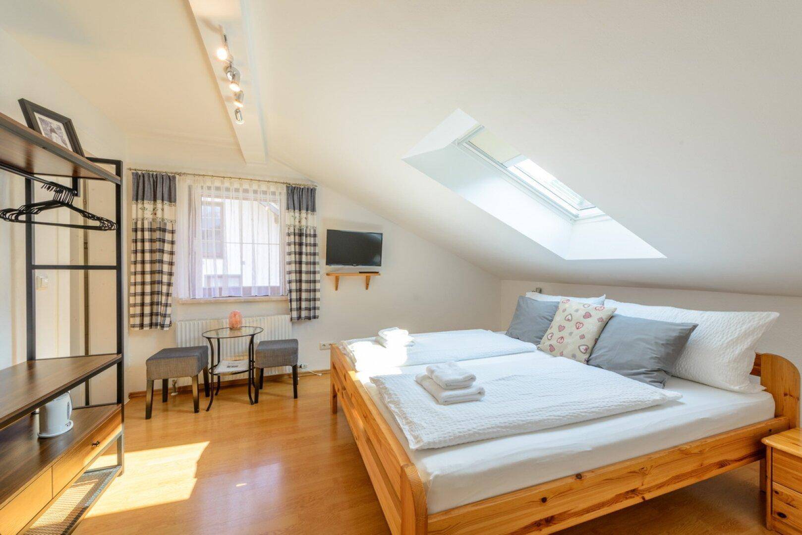 Helles Schlafzimmer im Dachgeschoss mit Holzboden, Dachschräge und viel Tageslicht.