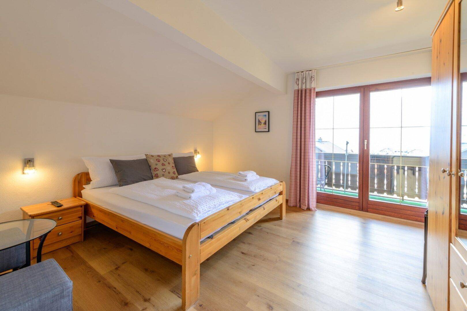 Geräumiges Schlafzimmer mit Holzboden und direktem Zugang zum Balkon.
