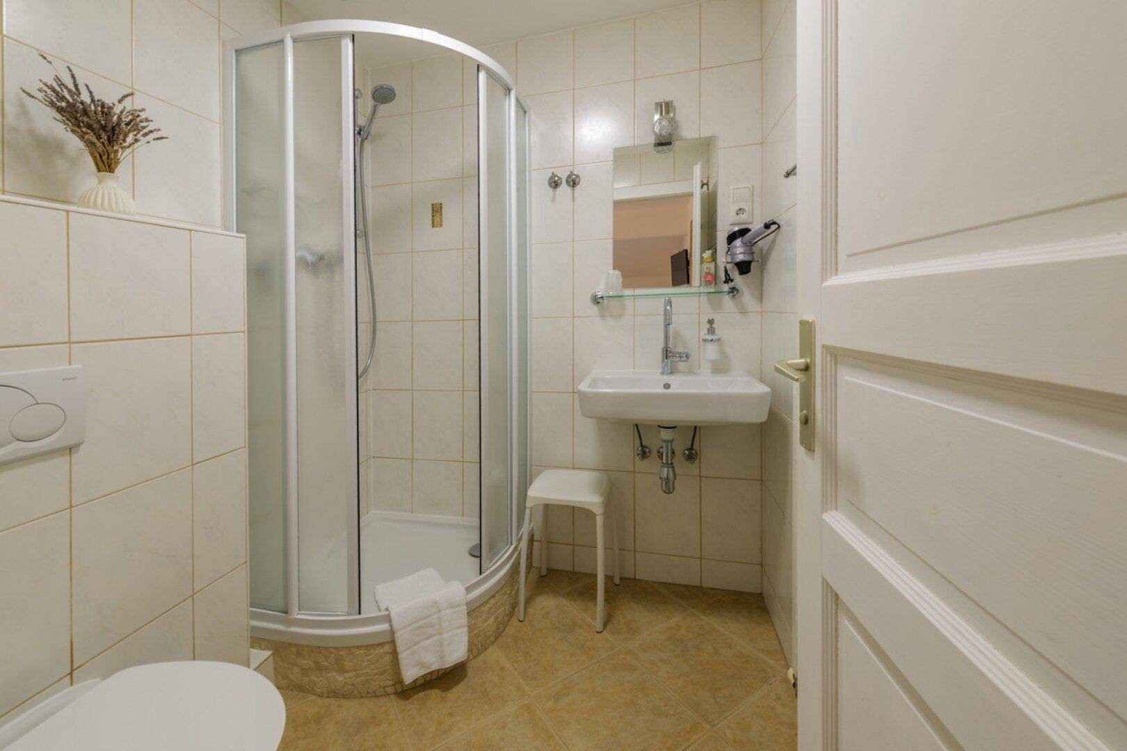 Kompaktes Badezimmer mit Duschkabine, WC und Fliesenboden.