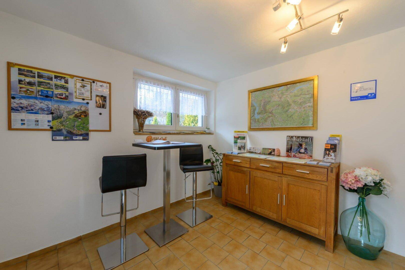 Informativer Empfangsbereich mit Bartisch, Holzschrank und lokalen Karten.
