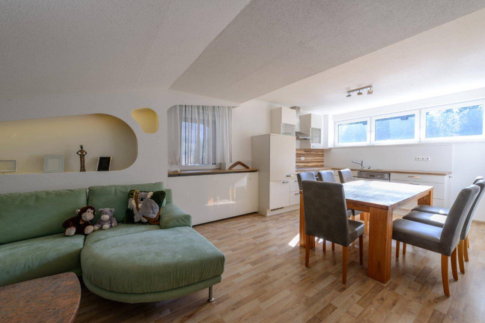 Gemütlicher Wohnbereich mit integrierter Küchenzeile, Esstisch und Sofa unter Dachschrägen.