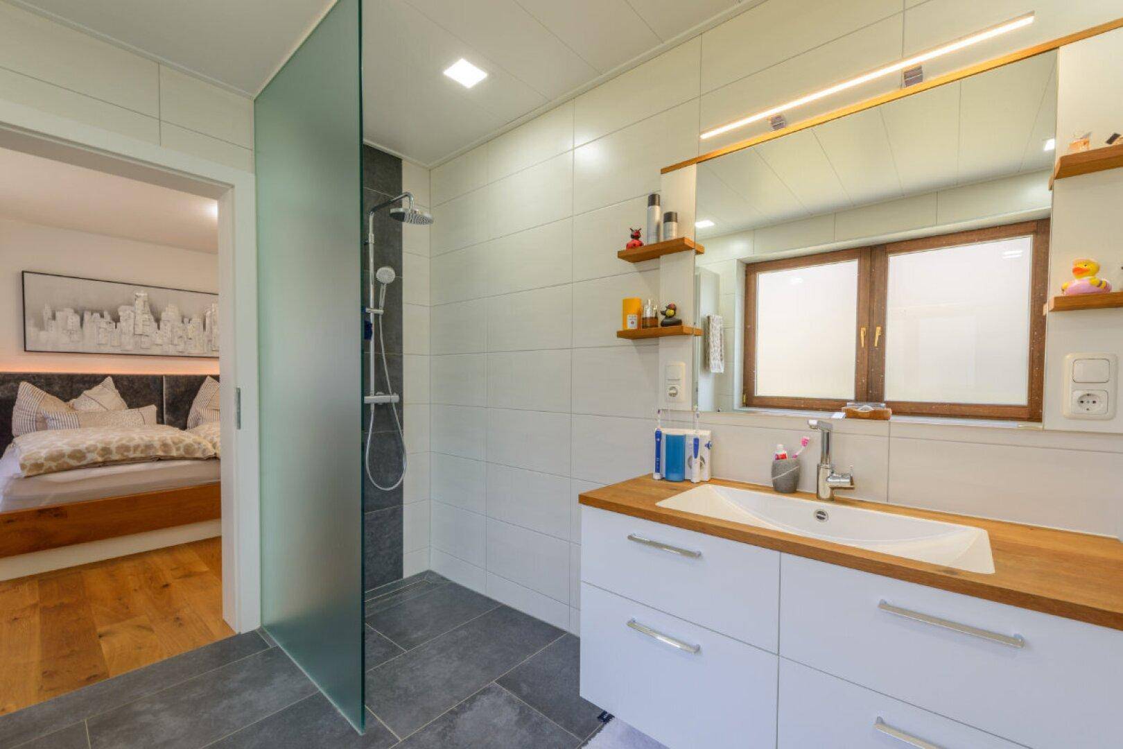 Modernes Badezimmer mit begehbarer Dusche und direktem Zugang zum Schlafzimmer.
