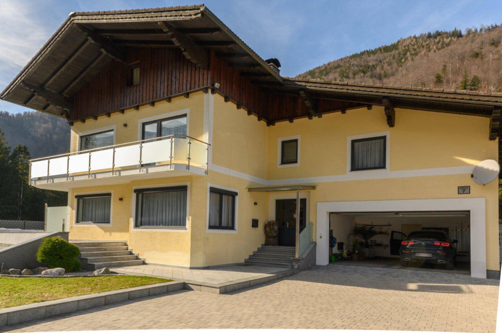 Vorderansicht des Wohnhauses mit Garage, Balkon und gepflegtem Vorgarten.