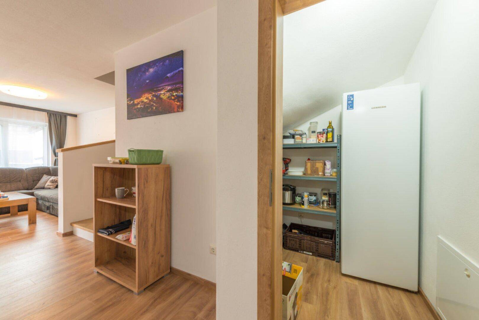Praktischer Abstellraum mit Regalen und großem Kühlschrank, angrenzend an den Wohnbereich.