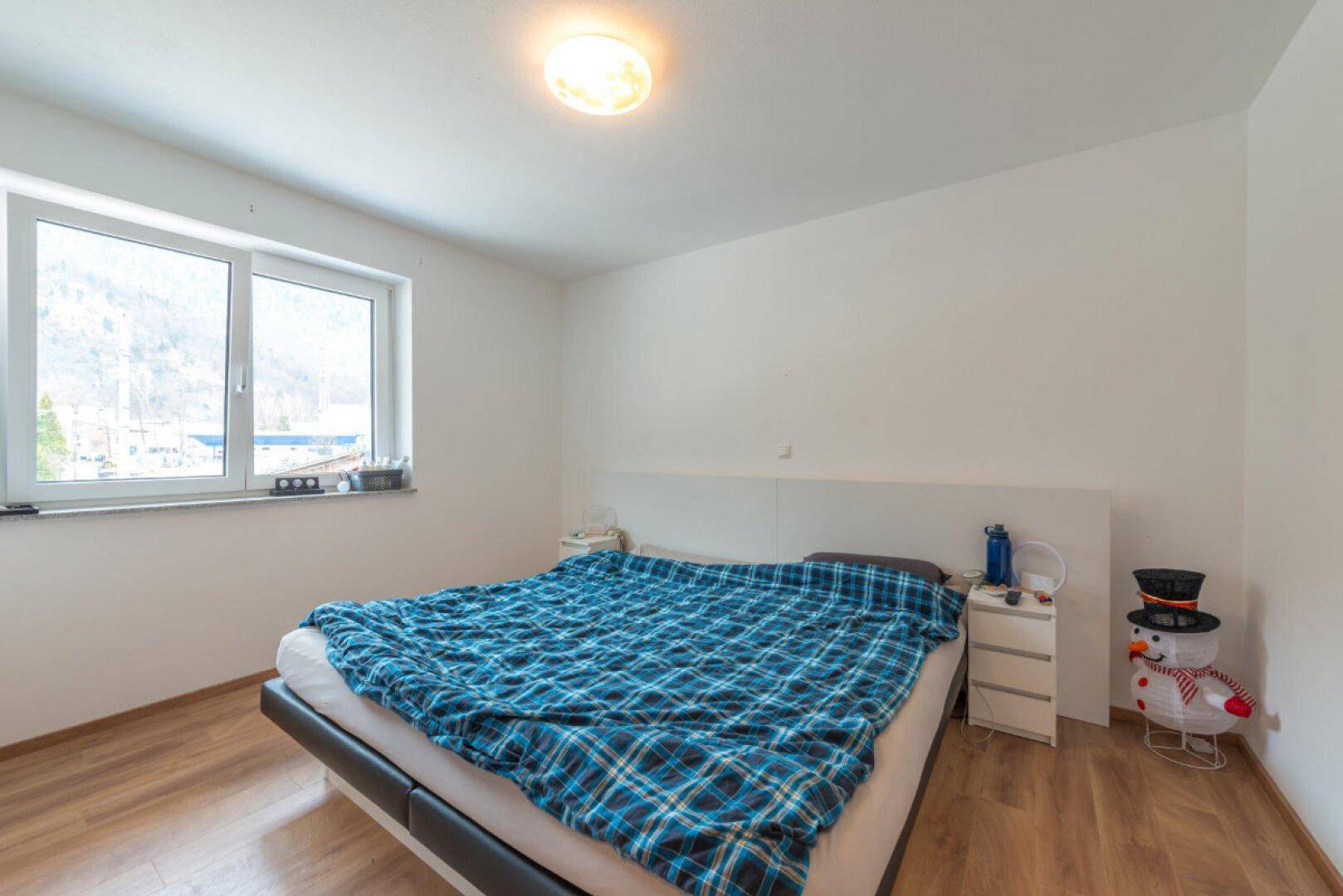 Gemütliches Schlafzimmer mit Doppelbett, Holzfußboden und Fenster mit Bergblick.