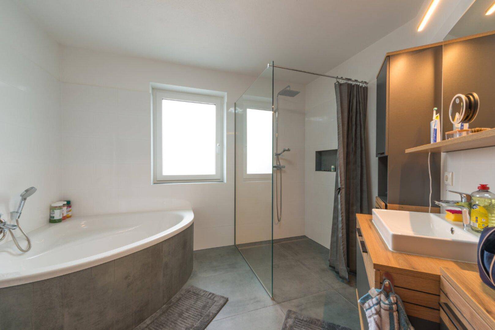 Modernes Badezimmer mit Eckbadewanne, begehbarer Dusche und Holzwaschtisch.