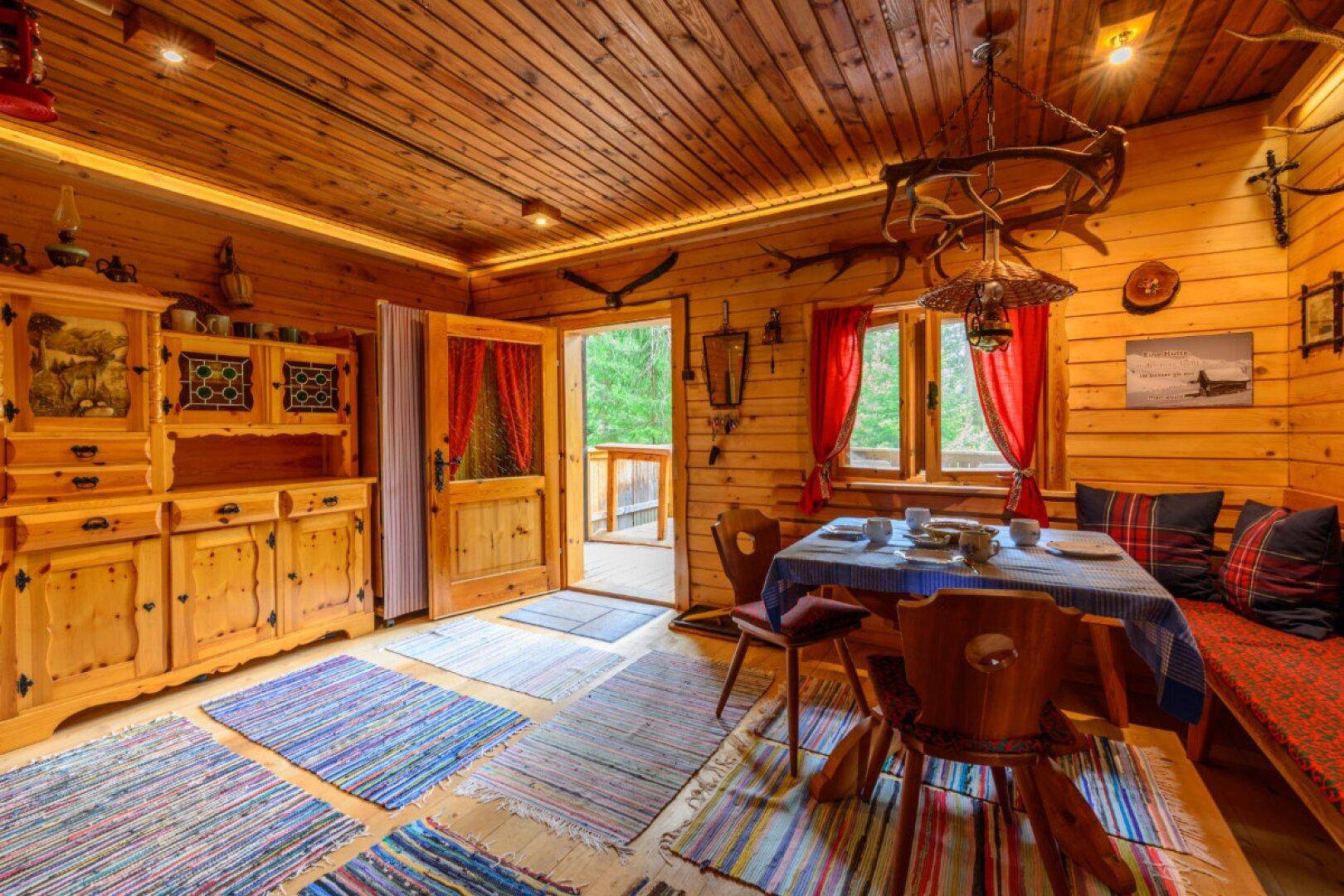 Gemütlicher Essbereich in einer Holzhütte mit traditionellen Möbeln und bunten Teppichen.