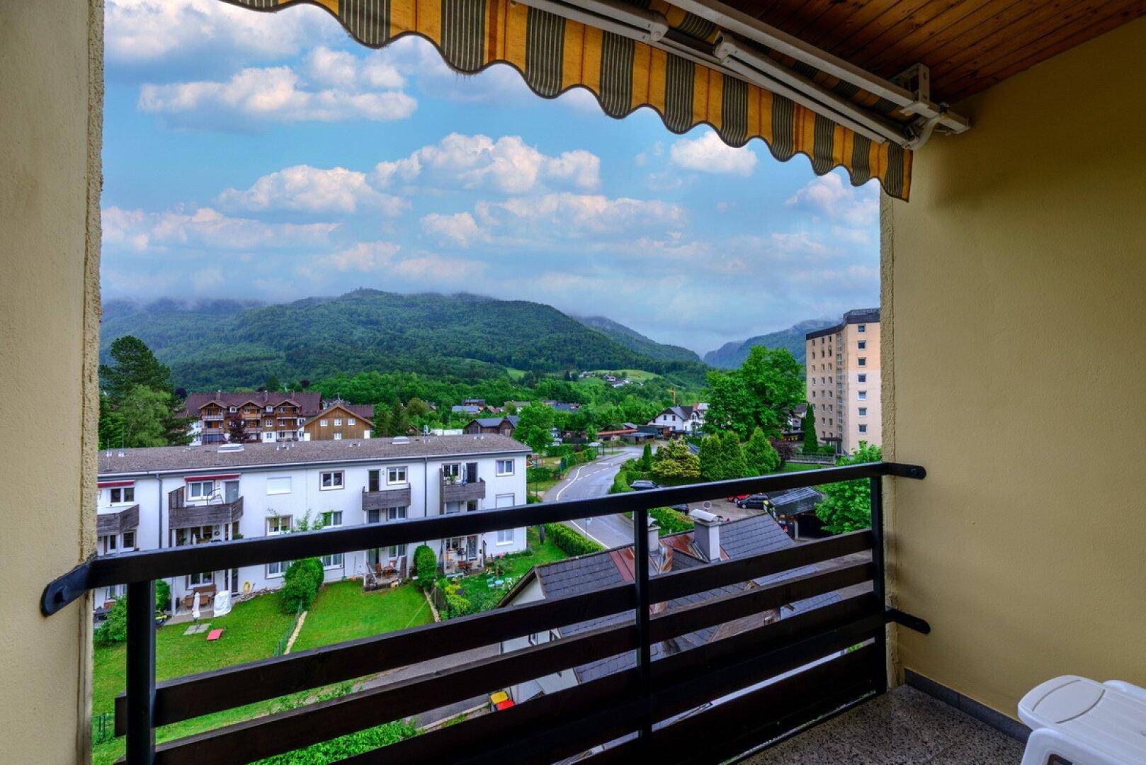 Balkon mit Markise und weitem Blick auf die umliegende Berglandschaft und die Stadt.