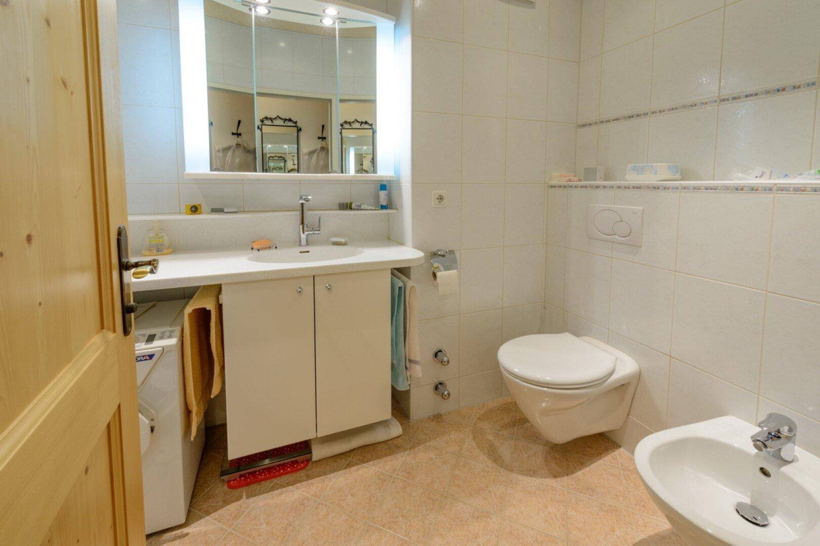 Badezimmer mit WC, Bidet, Waschbecken und integrierter Waschmaschine unter dem Waschtisch.