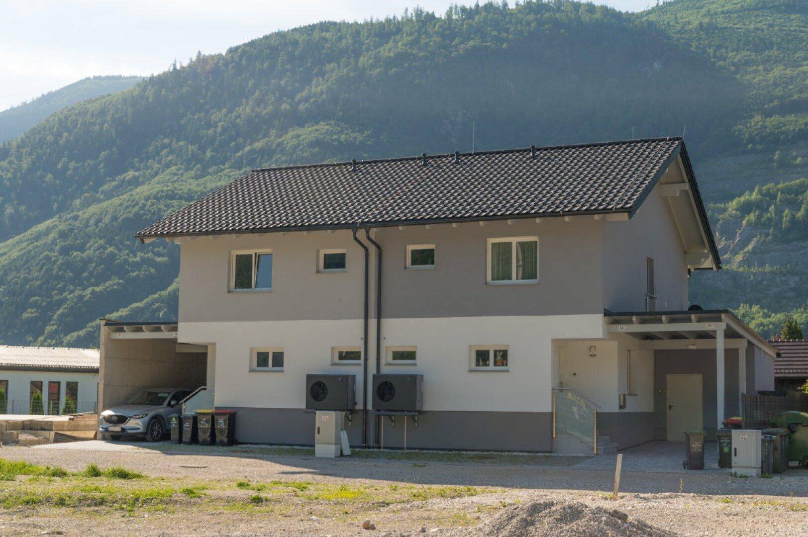 Rückansicht der Doppelhaushälfte mit Wärmepumpen und Bergblick.