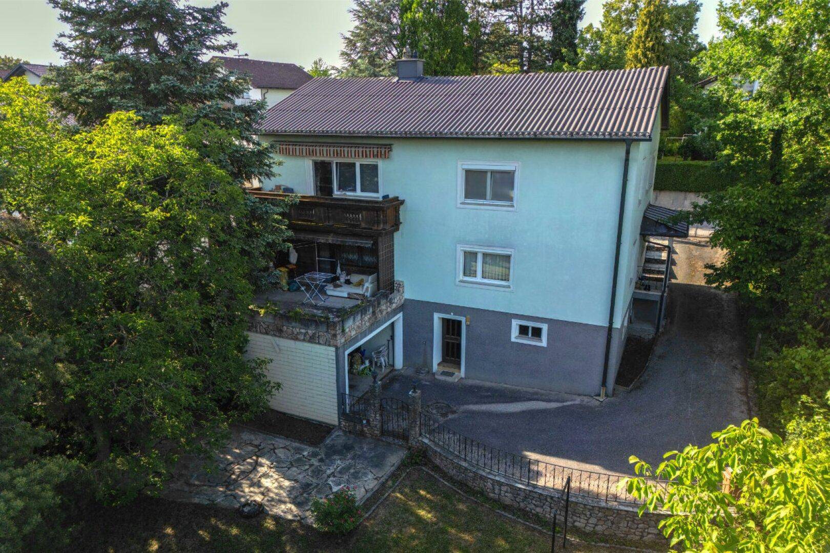 Luftaufnahme des Wohnhauses mit Balkon, Garage und umliegender grüner Landschaft.