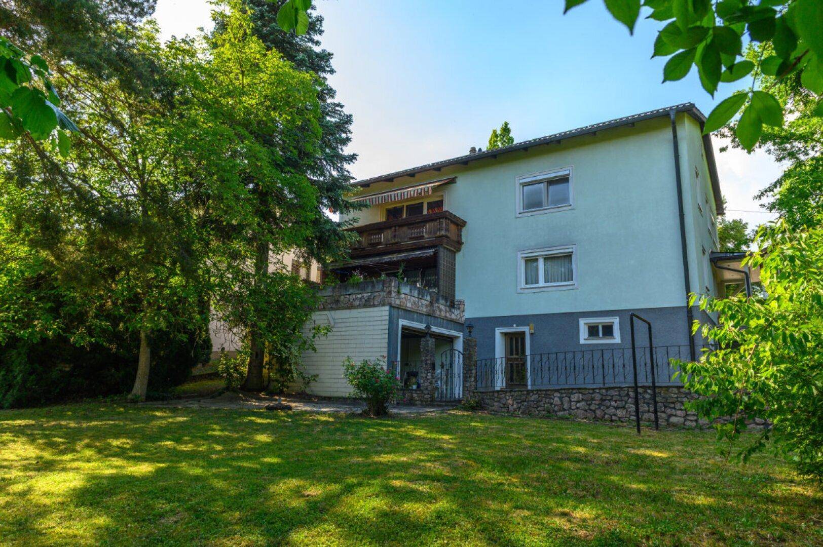 Rückansicht des Hauses vom Garten aus mit Balkon und grüner Umgebung.