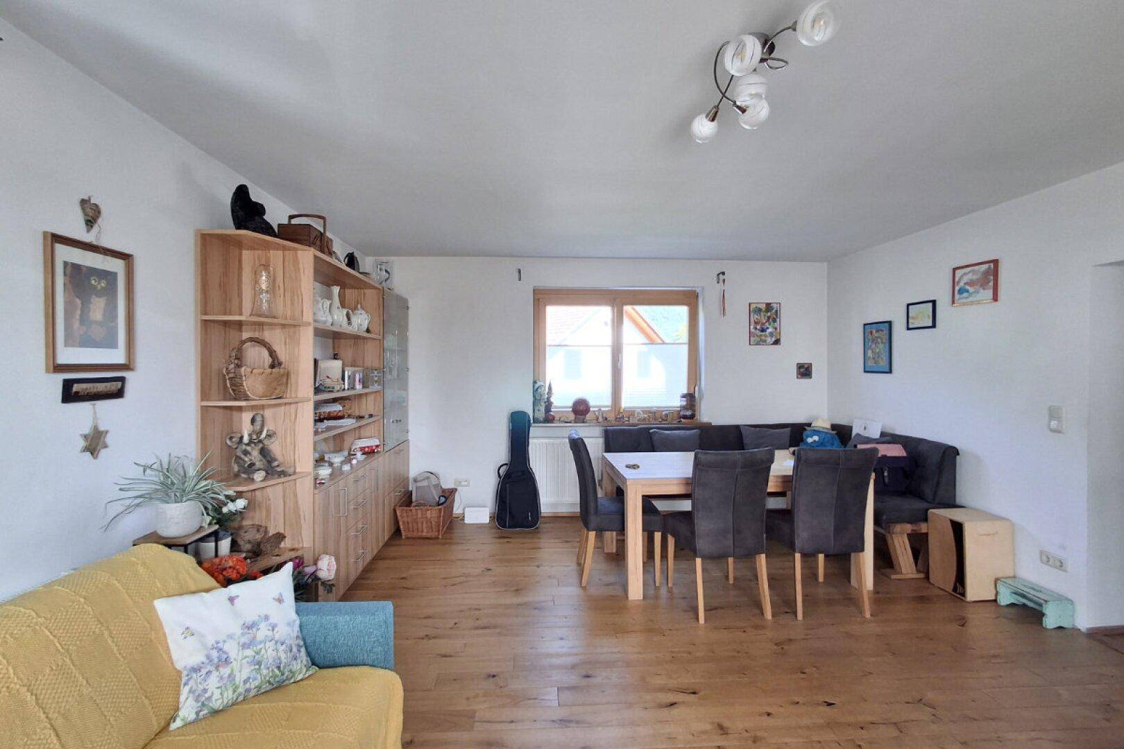 Geräumiger Wohn-Essbereich mit Holzboden, großem Esstisch und Sofa.