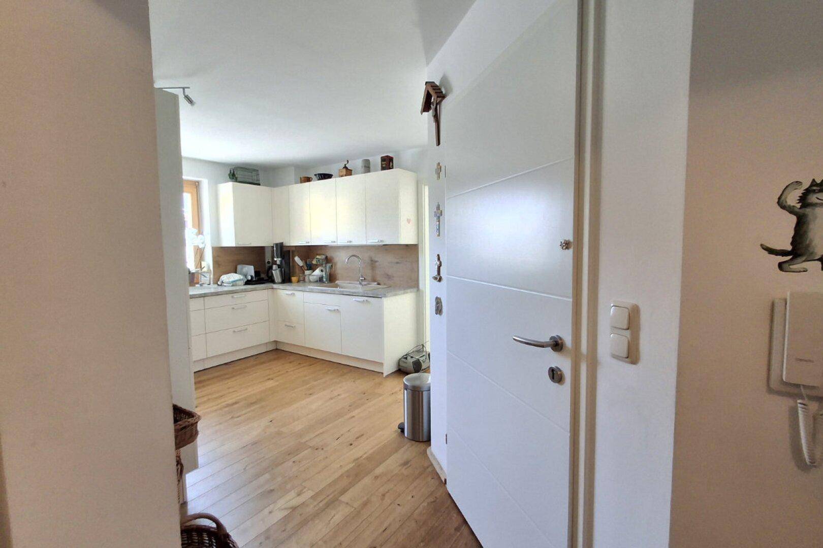 Eingangsbereich mit Blick in die moderne Küche mit weißen Schränken.
