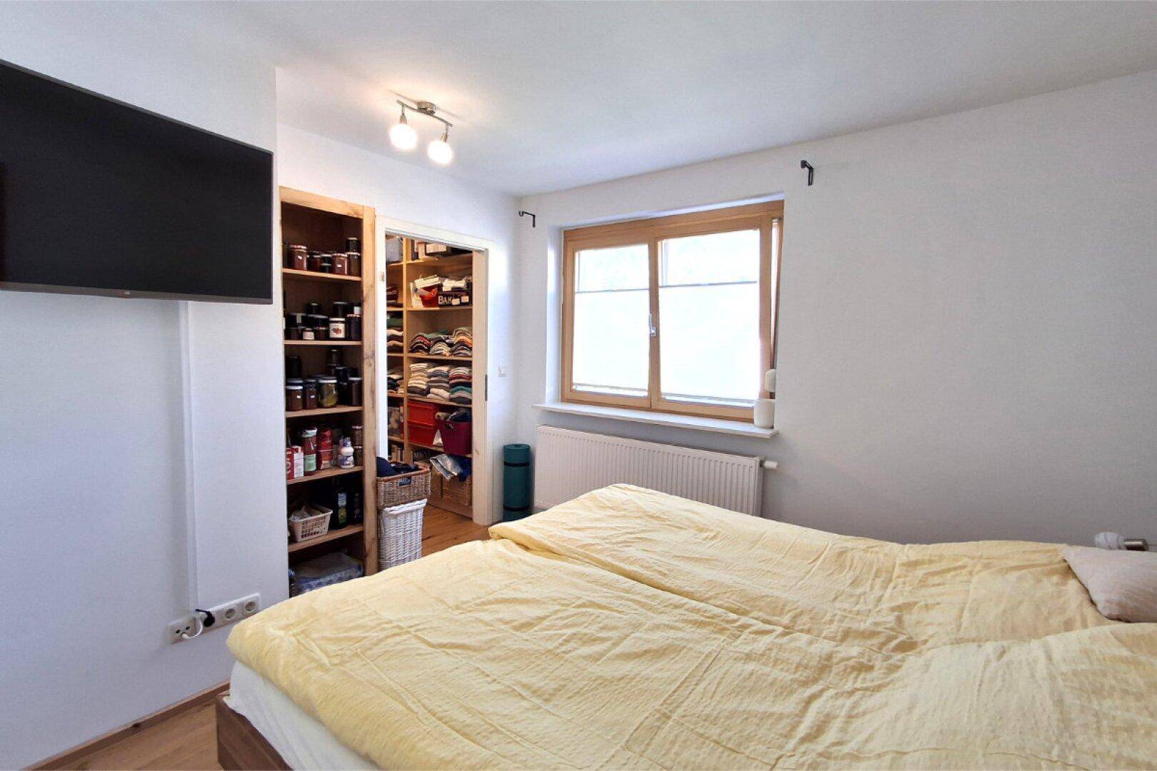Schlafzimmer mit Zugang zu einem begehbaren Kleiderschrank und Fenster.
